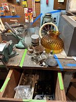 Photo of green Embury Air Pilot lantern, amber hobnail glass shade, metal parts and assorted lamp components on workbench