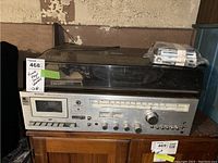 Front view of Sharp SG-200 stereo music center with cassette deck and record player dust cover on top.