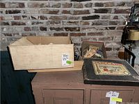 Wide shot of the lot including cardboard box, wooden tray, and Meccano box on cabinet against brick wall