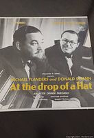 Black and white cover of 'At the Drop of a Hat' album featuring Michael Flanders and Donald Swann in formal wear.