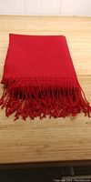 Folded bright red pashmina showing knotted fringe detail on one end