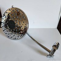 Close-up of large round chrome rainfall showerhead showing multiple water nozzles and reflective surface.