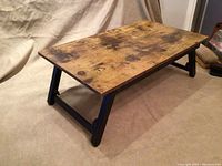 Top view of wooden lap desk with natural wood surface and black folding legs extended.