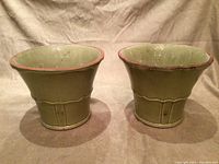 Pair of matching glazed terracotta pots set side by side on a fabric surface showing overall shape and colors