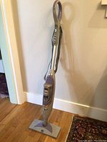 Full view of Shark SK460C steam mop standing against a wall on hardwood floor.