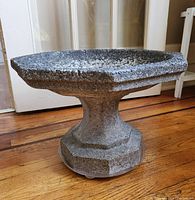 Side angle view showing the octagonal pedestal base and aggregate textured concrete basin of the bird bath.