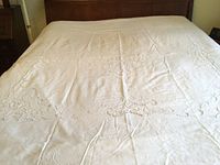 Full view of queen size white duvet cover laid out on bed, showing overall condition and central embroidery.