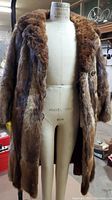 Front view of fur coat on dress form showing length, button closures and fur texture