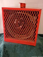 Front view of heavy duty electric heater showing red metal mesh grill and internal fan.
