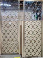 Full view of two bronze braised glass window panels side by side, showing outline and jewel accents.