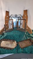 Photo showing two wooden picture frames, two wooden stretchers behind, two metal trays in foreground, and a hanging metal mirror in background.