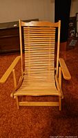 Front view of bamboo folding lounge chair showing slatted back and seat with armrests.