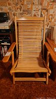 Front view of the bamboo folding lounge chair showing slatted backrest and armrests, natural wood finish.