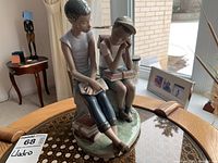 Side and front view of Lladro porcelain figurine showing two children sitting on a bench with books.