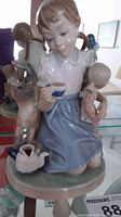 Front view of Lladro porcelain figurine showing girl holding teacup and cat standing beside her with teapot on base.
