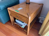 Side angle showing the wooden side table with drawer and contents on lower shelf.