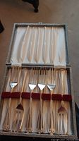 Set of six silver plated dessert forks neatly arranged in fitted box with cream and red velvet lining.