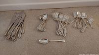 Overview of forks, spoons, and knives laid out on carpet
