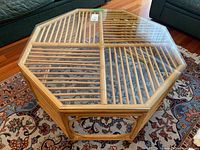 Top view of octagonal rattan coffee table with glass top showing the slatted design and clear glass covering.