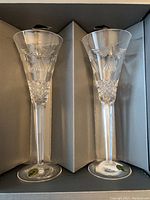 Pair of Waterford crystal champagne flutes in a box show front and side engraved designs