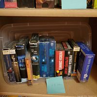 Photo showing a plastic bin containing 11 audio books on CD with visible titles and publishers.