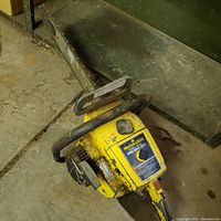 Side view of McCulloch Pro Mac 850 gas powered chain saw showing yellow painted engine cover, guide bar, chain, and black handle grips.