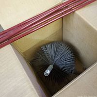 Box containing chimney brush with round wire bristle head and several long red metal extension rods.