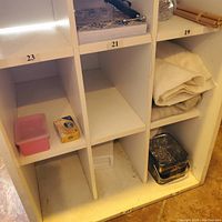 Front view of bottom three cubbyholes showing some items inside (not included) and condition of cabinet interior and surface.