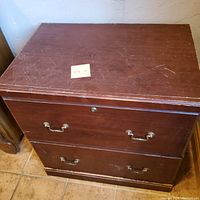 Top front view of Sauder two drawer wood file cabinet, showing scratches and wear on wood surface.