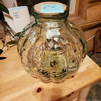Clear round glass vase with textured scalloped panels and cork stopper shown from two angles on wooden surface.