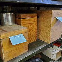 Three wooden boxes on a shelf, closed, showing storage containers for the tools.