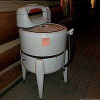 Full view of vintage electric wringer washing machine showing wringer, tub lid, legs, hoses and electrical cord.