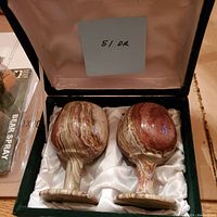 Two carved banded onyx stone goblets inside a lined box, showing their pattern and shape.