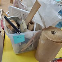 Photo showing plastic container with various brushes with wooden and plastic handles, paint tray cover, rolls of masking/kraft paper and painter's tape inside.