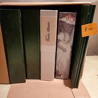 Photo showing 5 photo albums with different covers including green, white magnetic album, and vintage style girl image album