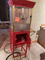 Front view of red popcorn machine on wheeled cart