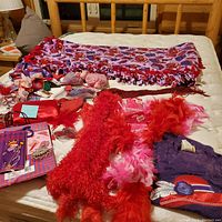 Lot items spread out on bed: fleece shawl, feather boas, small accessories, and collectibles.