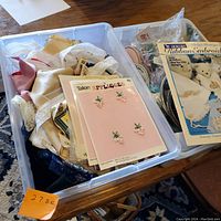 Two plastic tubs filled with assorted ribbon embroidery supplies including lace trims, rolls of ribbon, appliques, and embroidery floss.