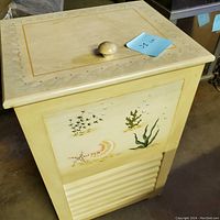 Front view of the small wooden hamper showing the sea-themed painted designs on the front panel and hinged top lid with knob handle.