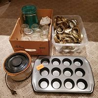 Overview photo showing small Rival crock pot, Wilton muffin tin, clear canning jars in box, and large container with metal canning rings.