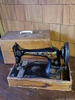 Full view of the vintage Singer sewing machine set in a wooden box with carrying handle, showing overall condition and patina.