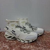 Side view of both shoes showing the blade-like sole and knitted upper