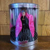 Barbie doll in original packaging, dressed in black gown with silver sparkles and pink shawl.