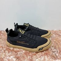 Side view of black fabric men's sport shoe with tan rubber sole and decorative gold text.