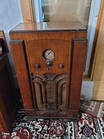 Front view of vintage Stromberg Carlson radio tuner with octagonal dial and wooden knobs on an oriental rug.