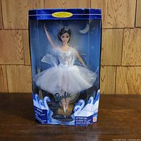 Front view of Barbie doll in original box showing doll in white tutu with silver tiara and feather accents.