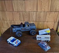 Four Tonka toy vehicles displayed on a wooden table with wood-paneled background.