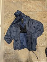 Navy blue Helly Hansen rain jacket laid out on tiled floor