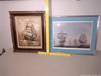 Both framed artworks side by side with measuring rulers placed vertically and horizontally for scale reference. The painting has a dark wood ornate frame and the print has a silver frame with blue mat.