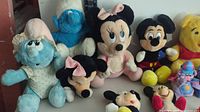 Photo showing several vintage stuffed animals including Smurf, blue teddy, Minnie Mouse, Mickey Mouse, and Winnie the Pooh.